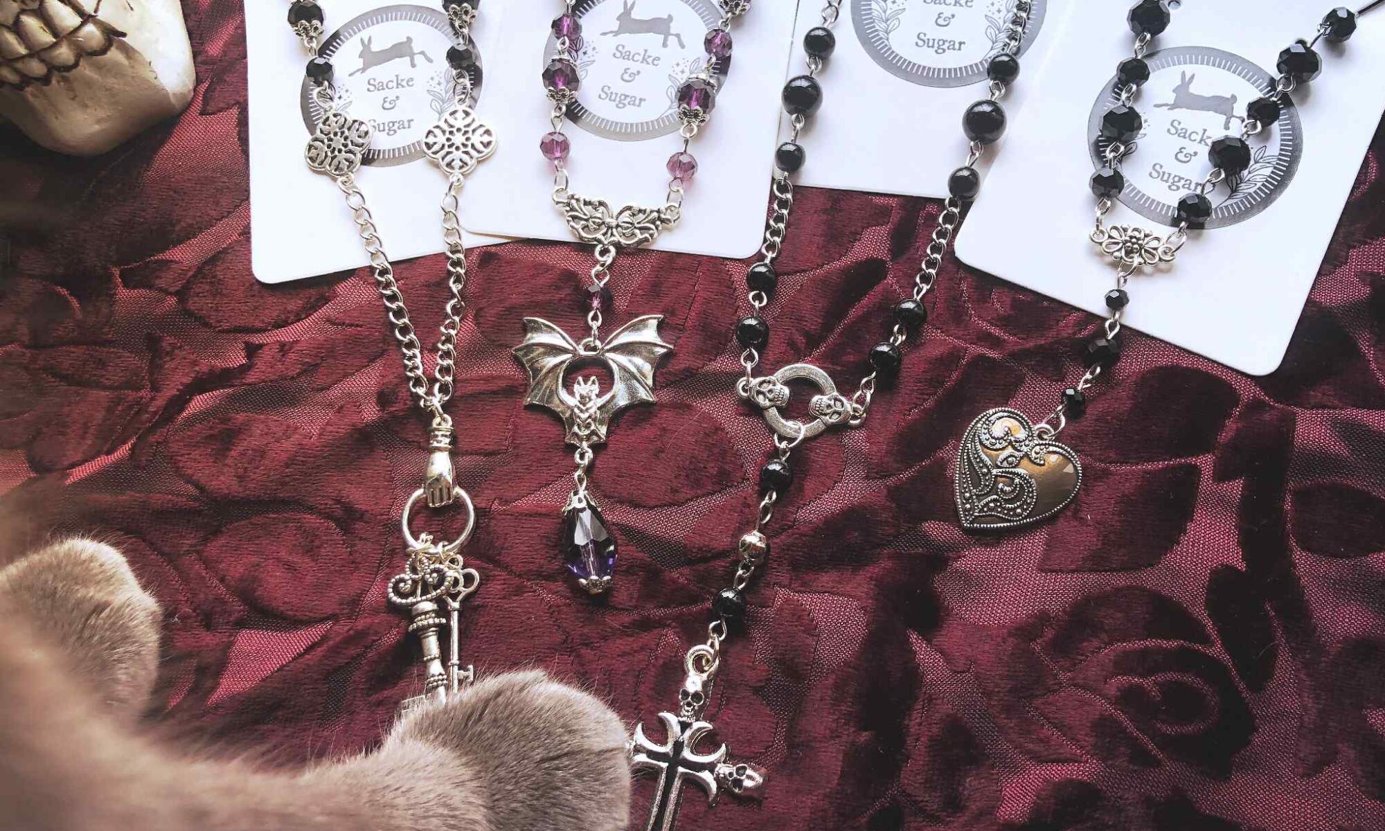 Sacke and Sugar jewelry laid out with a cat's paw in the corner